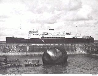 NAURU. 1941-01. PORT SIDE VIEW OF THE ARMED MERCHANT CRUISER HMAS MANOORA LYING OFF NAURU AFTER THE ATTACK ON THE ISLAND BY A GERMAN RAIDER THE PREVIOUS MONTH. NOTE THE DAMAGED BUOY IN THE ..