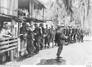 1943-01-21. PAPUA. BUNA. AMERICAN RE-INFORCEMENTS MOVE UP TO THE FRONT LINE, PAUSE AT A TRANSIT CAMP FOR A MEAL. (NEGATIVE BY BOTTOMLEY)