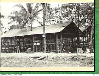 LAE, NEW GUINEA. 1944-03-24. VX100235 SERGEANT C. F. GERLOFF, TECHNICAL STOREMAN (BEHIND THE COUNTER), AUSTRALIAN FORTRESS WORKSHOP, WITH TROOPS OUTSIDE THE TECHNICAL STOREROOM AND "Q" STORE AT THE ..