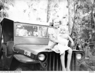 Ramale Mission, Kokopo Area, New Britain. A little Swedish girl, Marie Woolff, one of 300 white internees now at Ramale Mission, hold a young child. They were liberated when troops of HQ 11 ..