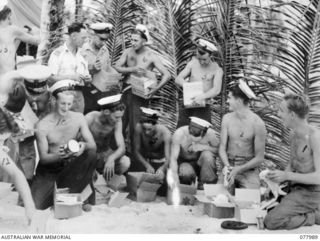 RAN personnel opening Christmas hampers issued by the Australian Comforts Fund representative at the 5th Base Sub Area. Identified personnel are: (left to right, crouching or kneeling) Signalman ..