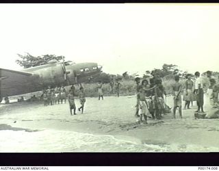 PORT MORESBY, NEW GUINEA. A "FLYING FORTRESS", NO. 12659 B17 BOMBER BOGGED IN SAND ON THE BEACH. A GROUP OF THE INHABITANTS INSPECT THE UNUSUAL SIGHT