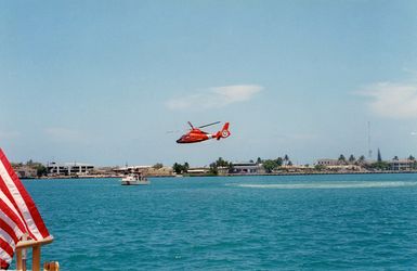 US Coast Guard (USCG) HH-65A Dolphin Search and Rescue (SAR) helicopter conducts a simulated water rescue with a USCG 41-foot Utility Boat (UTB 41317) in the harbor at Honolulu, Hawaii (HI), during a demonstration as part of Safe Boating Week