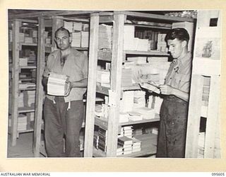 LAE AREA, NEW GUINEA. 1945-08-31. PRIVATE C.J. SHEEHAN (1) AND PRIVATE H.A. WISEMAN (2), AT WORK IN THE PUBLICATIONS SECTION, 9 LINES OF COMMUNICATION STATIONERY DEPOT