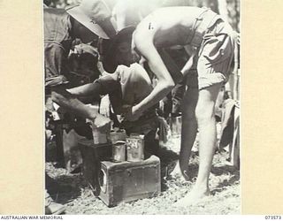 ALEXISHAFEN, NEW GUINEA. 1944-05-27. NX102929 PRIVATE K.W. WOODS, 35TH INFANTRY BATTALION (2), WITH PRIVATE SCHMIDT, C COMPANY, 533RD ENGINEER BOAT AND SHORE REGIMENT, UNITED STATES ARMY, PREPARES ..