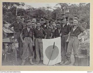 WONGINARA MISSION, NEW GUINEA. 1945-04-08. PERSONNEL OF "A" COMPANY, 2/3 INFANTRY BATTALION, AROUND A CAPTURED JAPANESE FLAG AND SWORD (FOR IDENTIFICATION OF 12 NAMED PERSONNEL REFER TO PROVISIONAL ..