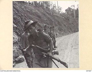 MOUNT SHIBURANGU, WEWAK AREA, NEW GUINEA. 1945-09-21. AN AUSTRALIAN SOLDIER OF HEADQUARTERS 6 DIVISION COLLECTING SWORDS AND WEAPONS FROM JAPANESE SOLDIERS OF 18 JAPANESE ARMY, AT A CONTROLLING ..