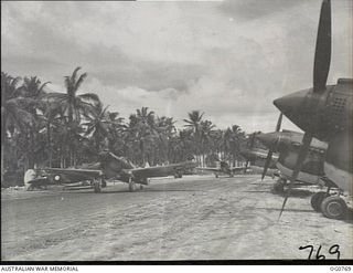 MOMOTE, LOS NEGROS ISLAND, ADMIRALTY ISLANDS. 1944-03-08. KITTYHAWK AIRCRAFT OF NO. 76 SQUADRON RAAF ON STAND-BY AT MOMOTE AIRSTRIP, BESIDE THE COCONUT PALM TREES, SCENE OF THE ORIGINAL LANDING IN ..