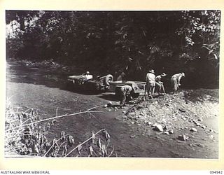 PARCHY RIVER, NEW GUINEA, 1945-07-23. ENGINEERS OF 10 PLATOON, 2/14TH FIELD COMPANY, ROYAL AUSTRALIAN ENGINEERS, LOADING GRAVEL ONTO A JEEP TRAILER FROM THE RIVER BED. IT IS ONLY USED TO STRENGTHEN ..