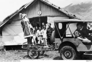 Ramu Valley, New Guinea. 1943-12-25. NX103434 Captain F. D. Smith, dressed as Father Christmas, arriving at one of the wards of the main dressing station, 2/6th Australian Field Ambulance, in a ..