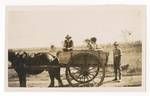 Group of people in horse lead wooden cart, one man stands behind the cart, 1920 to 1929