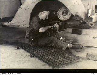 Port Moresby, New Guinea. 1944-04-10. VX89924 Corporal C. Bourke at the 11th Advance Workshop, Australian Electrical and Mechanical Engineers, replacing track rod ends on a Ford V8 vehicle