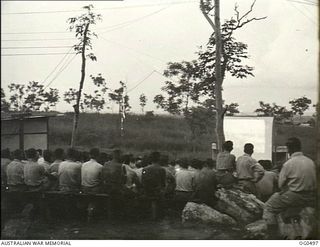 NEW GUINEA. 1944-01-08. AN APPRECIATIVE AUDIENCE WATCHING A FILM AT AN OUTDOOR PICTURE THEATRE AT A RAAF STATION IN THE AREA