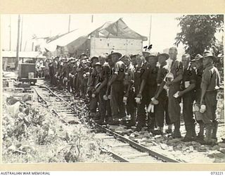 ALEXISHAFEN, NEW GUINEA. 1944-05. TROOPS OF THE 2/15TH FIELD AMBULANCE IN LINE FOR A MEAL DURING A MESS PARADE AT THEIR CAMP SITE LOCATED IN THE OLD CATHOLIC MISSION. THE TROLLEY LINES IN THE ..