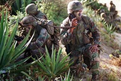 A US Marine Corps platoon leader and his radioman take cover along the beach at the Pacific Missile Range Facility, "Barking Sands" Kauai, HI. Marines from the 11th Marine Expeditionary Unit (MEU) Camp Pendleton, CA and involved Navy and Marine Air, Ground and Sea Forces trained as a combined amphibious assault force during Operation RIMPAC 96