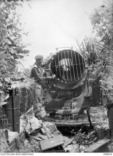 BALLALAE ISLAND, BOUGAINVILLE AREA. 1945-11-10. AN OFFICER OF 7 INFANTRY BATTALION EXAMINING ONE OF THE MANY HEAVY SEARCHLIGHTS WHICH ARE BUILT ON RAILS AND RUN BACK INTO HEAVILY FORTIFIED DUG-OUTS