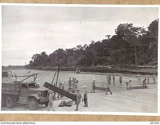 DREGER HARBOUR, NEW GUINEA. 1943-12-04. TROOPS OF THE 60TH UNITES STATES NAVAL CONSTRUCTION BATTALION (SEABEES) LAYING STEEL MATTING AT THE NORTH END OF THE NEW STRIP, WHICH, WHEN FINISHED, WILL BE ..