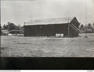 New Guinea. C. 1937. Exterior view of a thatched roof hangar building at a pre-World War II airfield in New Guinea
