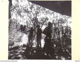 AWAR POINT, NEW GUINEA. 1944-07-09. MEMBERS OF NO.14 PLATOON, C COMPANY, 30TH INFANTRY BATTALION PUT THE BILLY ON FOR A CUP OF TEA BEFORE THE START OF AN EARLY MORNING PATROL. IDENTIFIED PERSONNEL ..