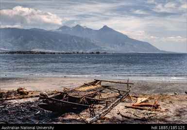 Canoes on the beach, view towards Goodenough Island with two canoes on the beach