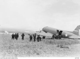 WANIGELA, NEW GUINEA. 1942-10. MEMBERS OF 3RD BATTALION, 128TH REGIMENT, 32ND U.S. DIVISION ALIGHTING FROM A 5TH US ARMY AIR FORCE (USAAF) C-47 TRANSPORT PLANE ON A ROUGH RUN WAY ON THE SHORES OF ..