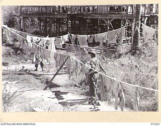 ALEXISHAFEN, NEW GUINEA. 1944-05-16. TX8315 LANCE CORPORAL P E FREWEN (1) AND VX63579 PRIVATE W A WALTERS (2), MEMBERS OF THE 2/15TH FIELD AMBULANCE, COLLECTING DRY LAUNDRY AT THE OLD CATHOLIC ..