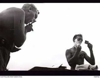 POMPOM VALLEY, NEW GUINEA. 1943-10-26. NX36087 PRIVATE E. A. COUCHMAN (LEFT) AND VX17148 CORPORAL R. A. CUTTS OF THE 7TH AUSTRALIAN DIVISION CONCERT PARTY, HAVING A SHAVE BEFORE THE SHOW