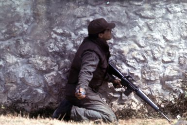 An Air Force security policemen prepares to toss a smoke grenade through the window of a "terrorist-held" building during an attack on the position. He is part of a group of policemen who are participating in anti-terrorist training being conducted by the Marine Brigade School