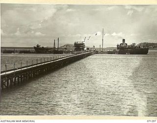 PORT MORESBY, PAPUA, 1944-03-21. THE EMPIRE SILVER, AN OIL TANKER BERTHED ON THE END OF THE WHARF, VIEWED FROM A HILL. THE PIPELINES RUNNING BESIDE THE PATHWAY AT THE WHARF ARE CONTROLLED BY THE ..