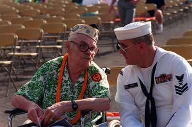 Raymond Sandlin, an Army Air Corps private who survived of the Dec. 7, 1941, attack on Pearl Harbor, listens to the U.S. Pacific Fleet Band with his escort, PO1 F. Scott Wilson, during Remembrance Day ceremonies at the USS ARIZONA Memorial Visitors Center. The event commemorates the 50th anniversary of the bombing