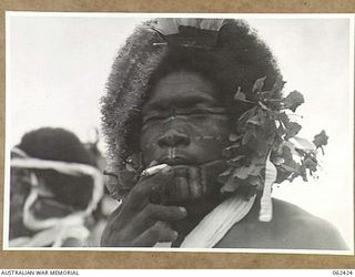 KILA, KILA, PAPUA, NEW GUINEA. 1943-12-25. A NATIVE OF THE MEKEO TRIBE DRESSED FOR THE DANCE WITH FLOWERS IN HIS HAIR AND AN OCHRE PAINTED FACE