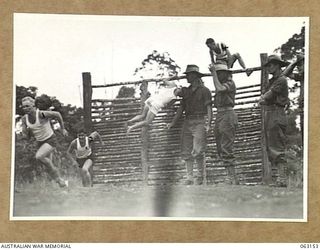 DONADABU, PAPUA, NEW GUINEA. 1944-01-01. CONTESTANTS SCALING THE SIX FOOT PALISADE IN THE OBSTACLE RACE AT THE 15TH INFANTRY BRIGADE GYMKHANA. IDENTIFIED PERSONNEL ARE: PRIVATE C. LEGG (1); PRIVATE ..