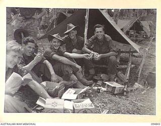 ILIPEM, NEW GUINEA, 1945-07-31. MEMBERS OF 11 PLATOON, B COMPANY, 2/5 INFANTRY BATTALION, ENJOYING THE BENEFITS OF THEIR NEWLY ARRIVED MID-YEAR AUSTRALIAN COMFORTS FUND HAMPERS