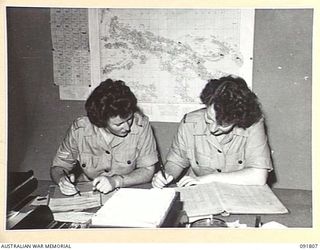 LAE, NEW GUINEA. 1945-05-15. CORPORAL J. PONTEFRACT (1), AND PRIVATE P. JOHNSTON (2), CHECKING OFFICERS' PERSONAL RECORDS AT HEADQUARTERS FIRST ARMY. A FEW DAYS AFTER THEIR ARRIVAL FROM AUSTRALIA ..