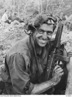 1943-09-14. NEW GUINEA. KOMIATUM RIDGE. CPL. BILL MCDONNELL, OF ORMOND, VIC., WITH HIS FACE SMEARED WITH CAMOUFLAGE GREEN PAINT. MCDONNELL HAD JUST RETURNED FROM THE FIGHTING PATROL ON KOMIATUM ..