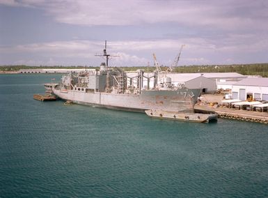 A starboard view of the combat stores ship USS SAN JOSE (AFS-7) with a paint barge positioned alongside at the U.S. Naval Ship Repair Facility