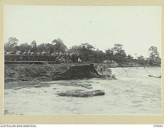 LAE, NEW GUINEA. 1944-08-09. TROOPS OF THE 20TH FIELD COMPANY, "NOSING" THE FIRST SPAN OF A NEW BRIDGE ACROSS THE BUTIBUM RIVER WHICH IS TO REPLACE THE OLD ONE WHICH WAS WASHED AWAY DURING THE ..