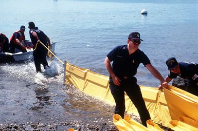 Members of the Coast Guard Marine Safet6y Office, Honolulu, set up an oil spill containment boom during a training exercise