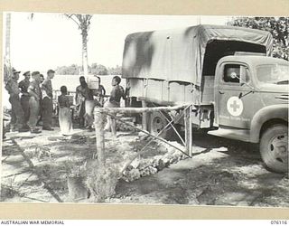 MILILAT, NEW GUINEA. 1944-09-21. PERSONNEL OF THE AUSTRALIAN RED CROSS SOCIETY ATTACHED TO HEADQUARTERS 5TH DIVISION WATCH THE UNLOADING OF SUPPLEMENTARY RATIONS FOR NATIVES IN THE AUSTRALIAN NEW ..