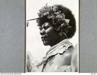 KILA, KILA, PAPUA, NEW GUINEA. 1943-12-25. A NATIVE OF THE MEKEO TRIBE DRESSED FOR THE DANCE WITH FLOWERS IN HIS HAIR AND AN OCHRE PAINTED FACE