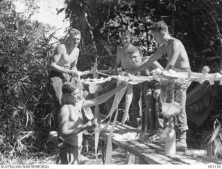 FINSCHHAFEN, NEW GUINEA. 1943-12-25. PERSONNEL OF THE 2/3RD PIONEER BATTALION DECORATING THEIR MESS TABLES IN PREPARATION FOR THEIR CHRISTMAS DINNER. SHOWN ARE: NX59291 PRIVATE R. G. COADY (1); ..