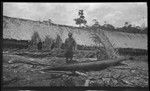 Man in front of long house, canoe hear him