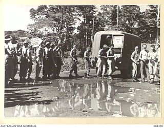 LAE AREA, NEW GUINEA. 1944-12-20. 4 ADVANCED ORDNANCE DEPOT TROOPS HAVING THEIR MORNING BREAK OF TEA AND A "SMOKO" WITH SUPPLIES BROUGH TO THE FORWARD AREA BY A YMCA AUSTRALIAN COMFORTS FUND TRUCK