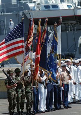 A joint service honor guard and color bearers stand at attention during a wreath laying ceremony for the Unknown Soldier of the Vietnam War. The flag draped casket will be transported aboard the frigate USS BREWERTON (FF 1086) to Alameda, California. Its final destination will be the Tomb of the Unknown Soldier at Arlington National Cemetery, Virginia