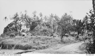 Oro Bay, New Guinea. 1943. The 83rd Anti-Aircraft Searchlight Battery's station. Buildings with walls of sandbags and wood or grass roofs are visible amongst the trees