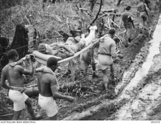 NATIVES CARRYING BACK A 58/59 INFANTRY BATTALION CASUALTY, WX26764 SERGEANT VICTOR COLE ROBERTS, OF DARRADUP,WA, WOUNDED DURING A PATROL CLASH WITH THE JAPANESE SOUTH OF THE POROREI RIVER. HEAVY ..