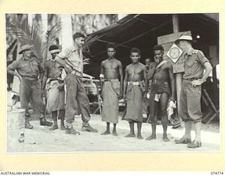 MILILAT, NEW GUINEA. 1944. AUSTRALIAN TROOPS AND NATIVES OUTSIDE THE RECREATION HUT WHICH IS RUN JOINTLY BY THE SALVATION ARMY AND THE AUSTRALIAN COMFORTS FUND SET AMONG THE COCONUT PALMS AT ..