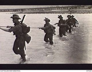 UMI RIVER, NEW GUINEA. 1943-09-29. TROOPS OF HEADQUARTERS, 21ST AUSTRALIAN INFANTRY BRIGADE CROSSING THE RIVER WITH THE ASSISTANCE OF A HAND ROPE. LEFT TO RIGHT: PRIVATE (PTE) K. L. MCKEON; ..