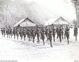 TOROKINA, BOUGAINVILLE, 1945-12-04. MEMBERS OF THE ROYAL PAPUAN CONSTABULARY PRESENT ARMS AS MAJOR- GENERAL W. BRIDGEFORD, GENERAL OFFICER COMMANDING 3 DIVISION, ARRIVES FOR A MEDAL PRESENTATION ..