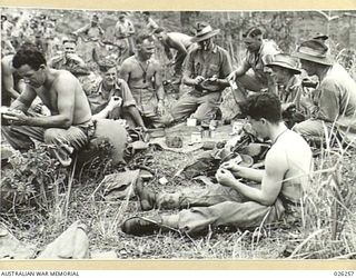 PAPUA. 1942-08. TROOPS OF THE 2/27TH AUSTRALIAN INFANTRY BATTALION EATING A MEAL IN THE OPEN AT THE SPOT IN THE KIKINUMU DISTRICT WHERE THEY BIVOUACED FOR THE NIGHT